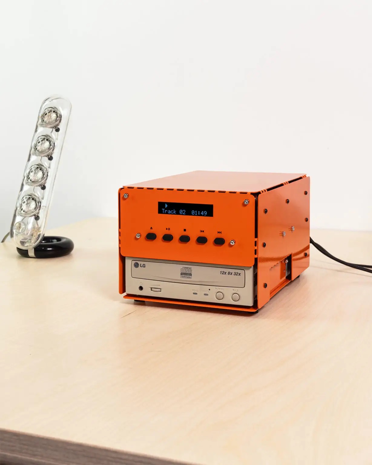 The das_POD CD-ROM PLAYER 01, a DIY aluminum kit built around a repurposed LG CD-ROM drive, shown in its orange finish on a desk