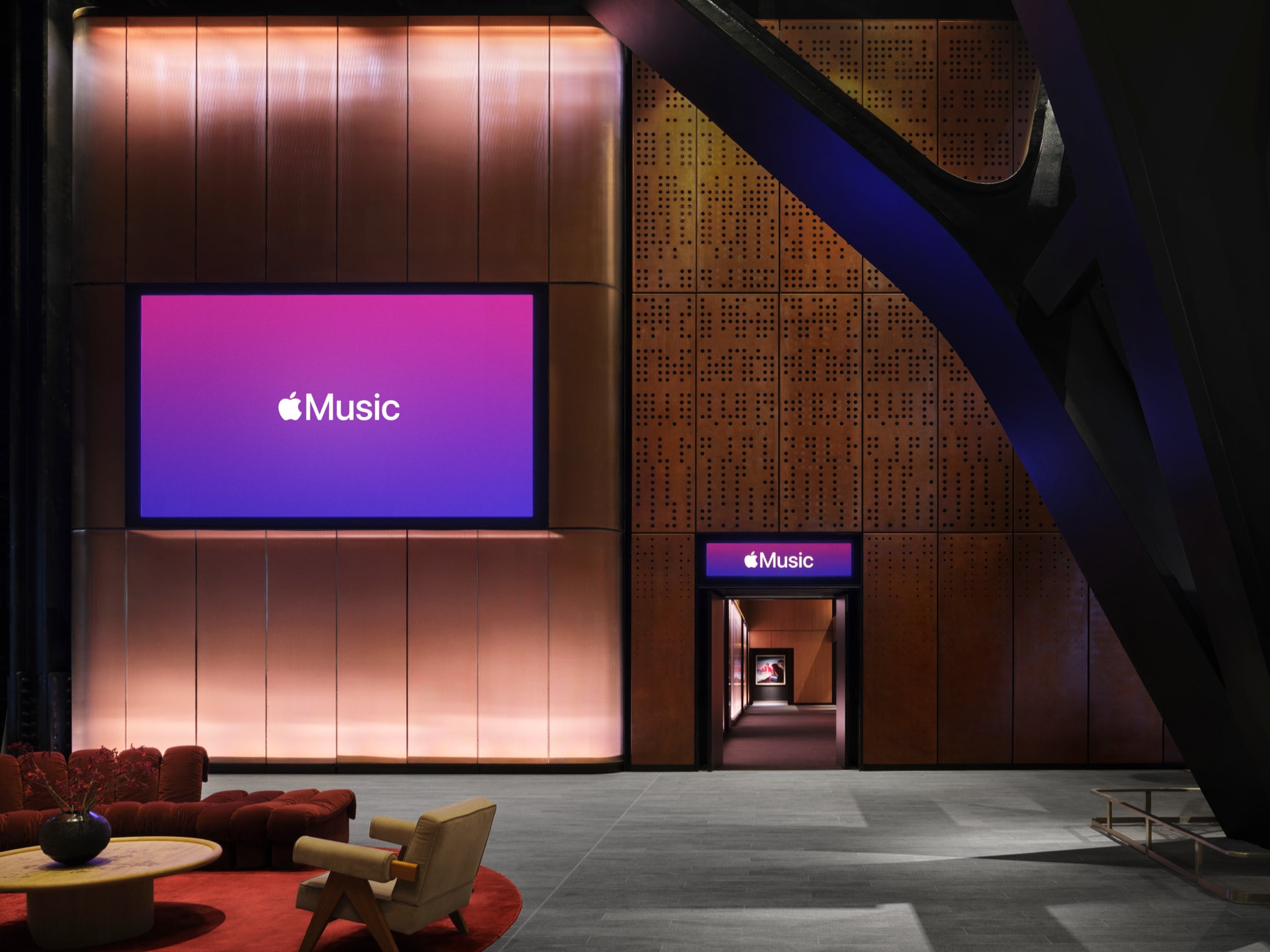 The Apple Music Hall foyer, with bronze panelling, an Apple Music branded screen and lounge seating leading toward the hall entrance
