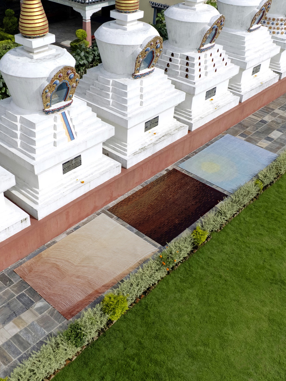 Zoometry rugs by Creative Matters and RDAI laid out near white stupas, patterns inspired by coral, sand ripples and insect wings