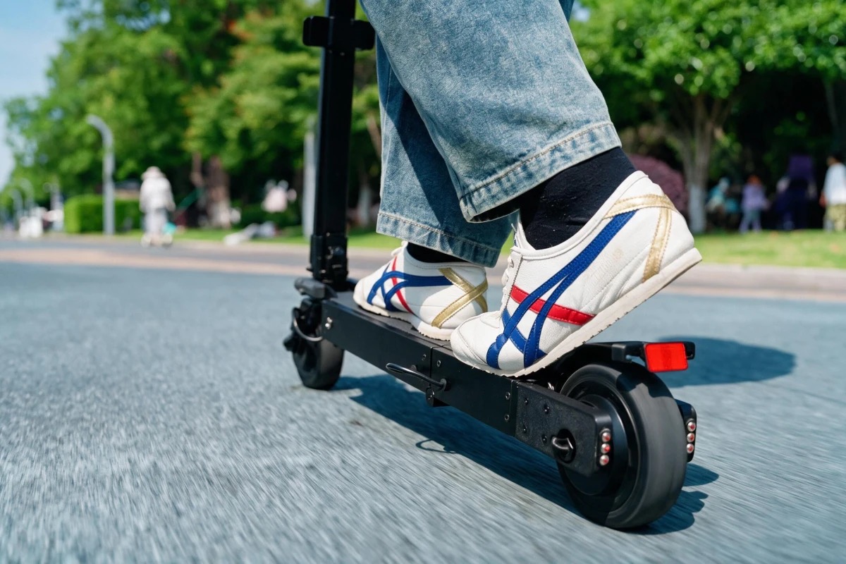 Close-up of a rider's feet on the unfolded Blizwheel F0.5 while riding along a paved path