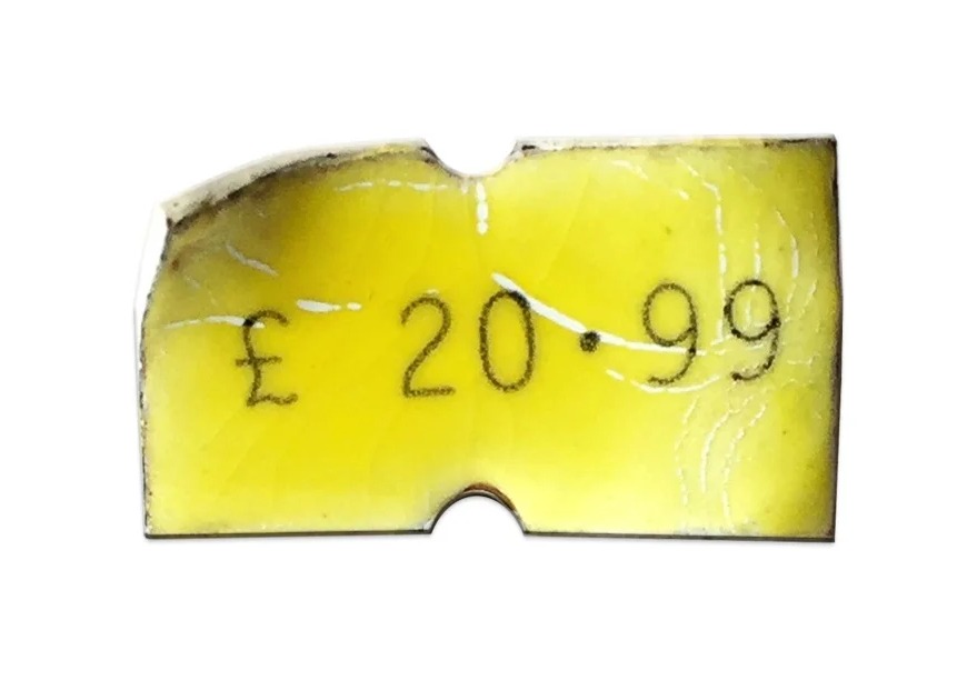 One of Lucie Davis's Precious Price Tag Pins in yellow enamel, showing the crackle texture and asymmetric cut edge that make each piece one of a kind
