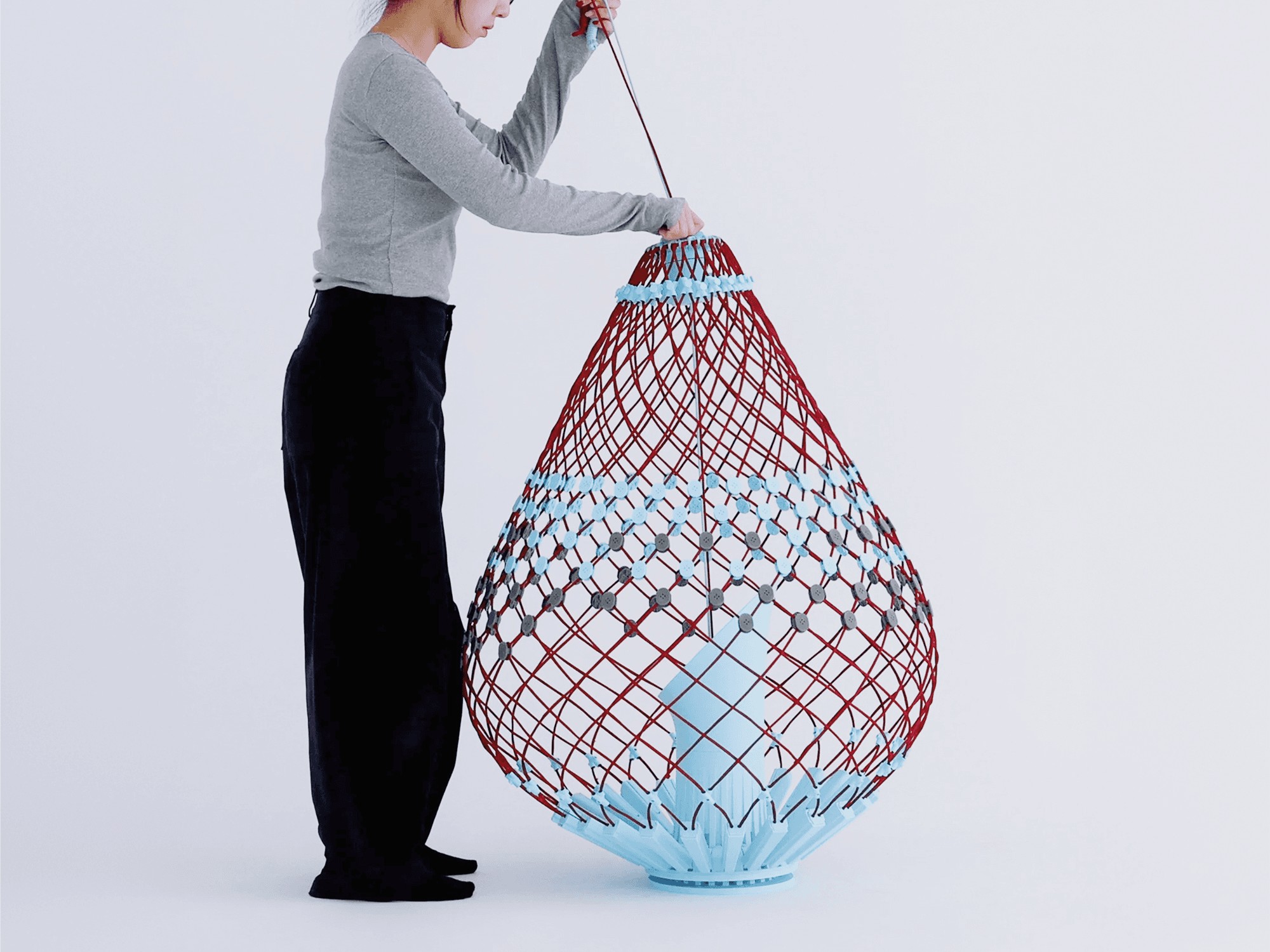 Jisu Yoon pulls a cord to deploy the Re-flat pack sofa from its collapsed column into its full seat form