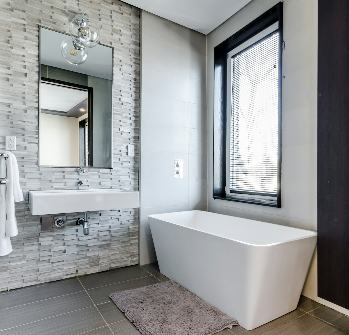 A sunlit bathroom niche with a freestanding tub set beneath a window