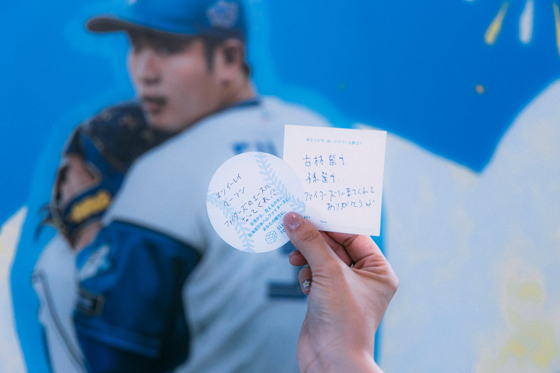 A fan holds up a handwritten cheer card for the Fighters' Taiwanese players at the SLEEPY TOFU activation