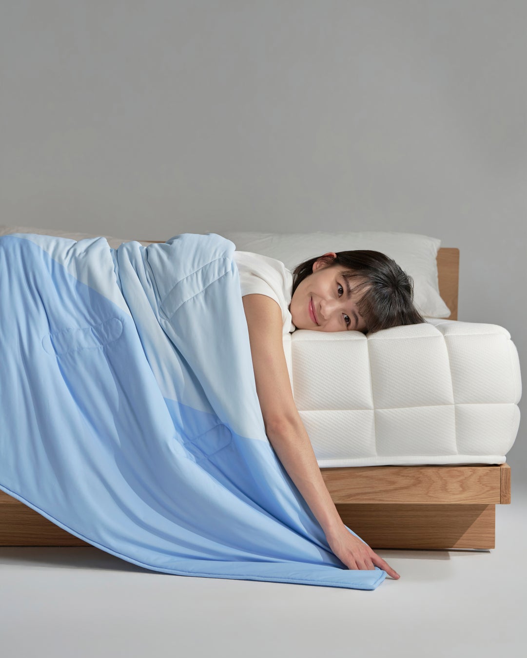 A model lies on SLEEPY TOFU's diced-grid mattress under the brand's Q-Max-rated cooling comforter