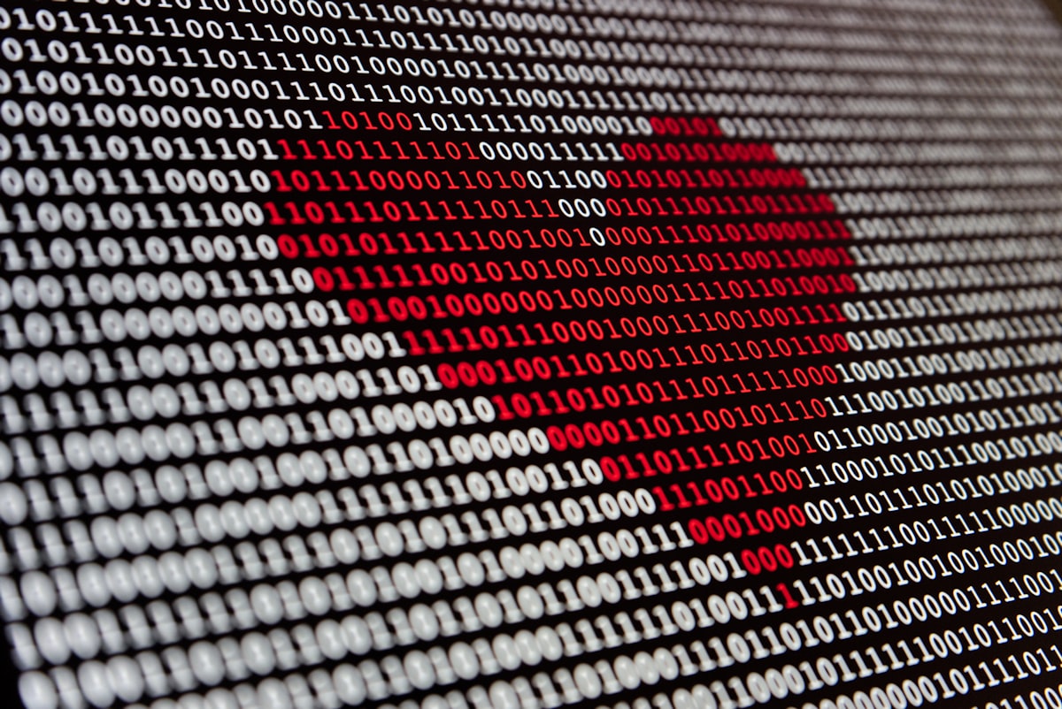 A heart shape formed out of red binary code on a computer screen