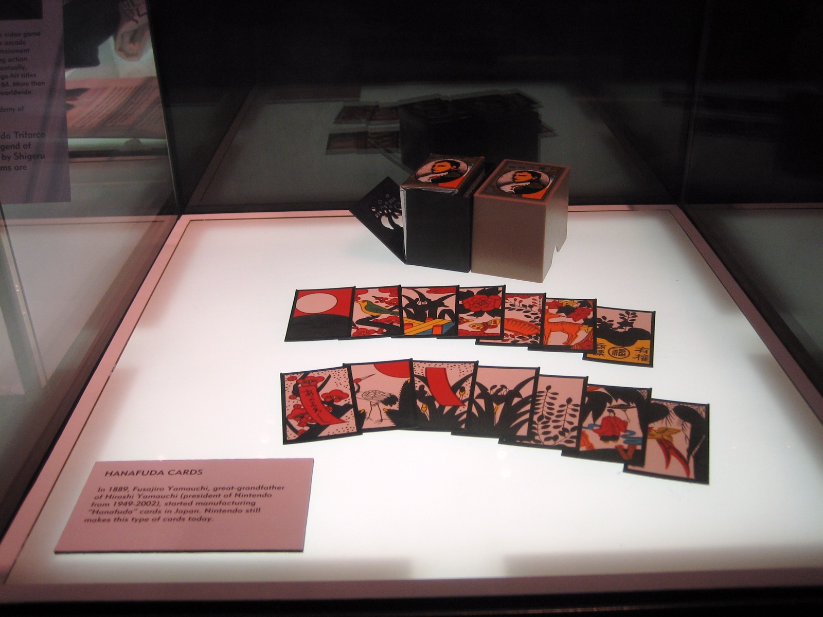 A museum display of Nintendo hanafuda cards and their original boxes, with an explanatory placard