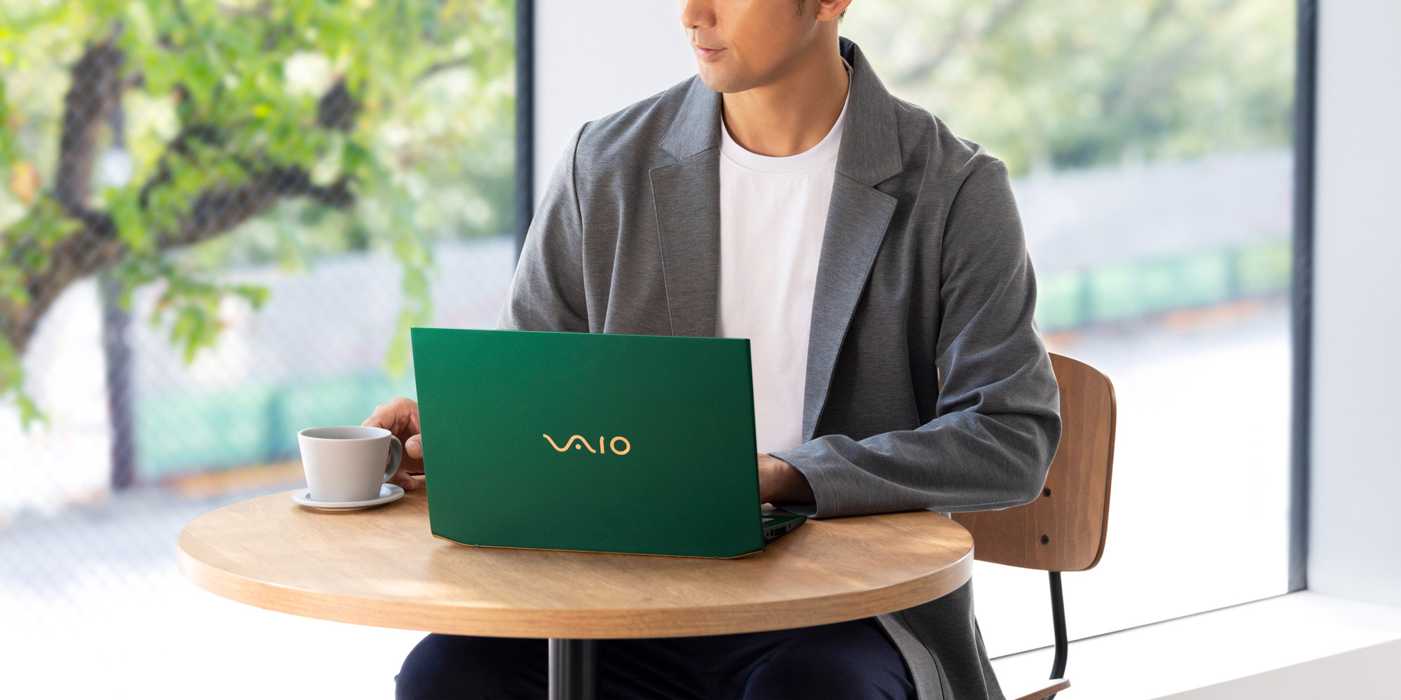 A person working at a café table, laptop closed, with no wearable device in sight